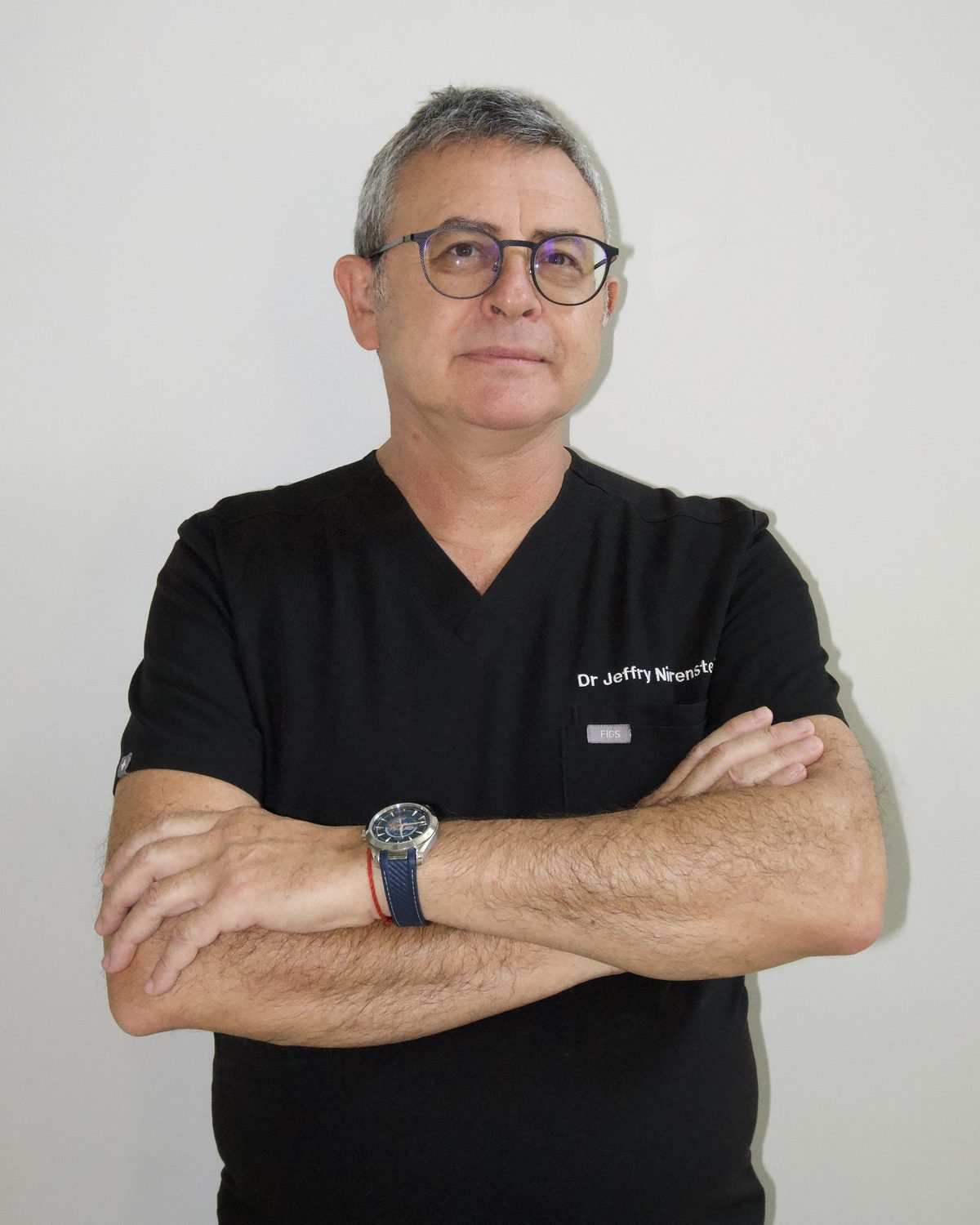Dr. Jeffry Nirenstein in black scrubs, arms crossed
